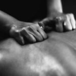 Physiotherapist massaging male patient with injured back muscle. Sports injury treatment.