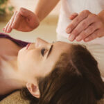 Young woman having a reiki treatment in therapy room Young woman having a reiki treatment in therapy room